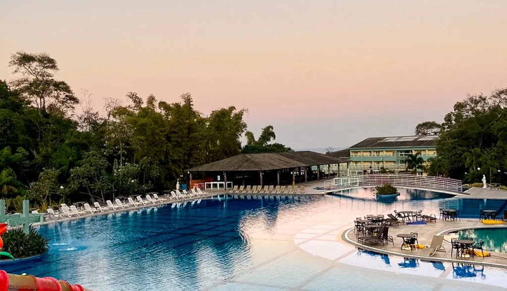 Vista da piscina e área de lazer do Itatiaia Resort & Eventos ao entardecer, com natureza ao redor e estrutura completa para hospedagem e eventos.
